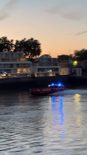 Fire rescue boat speeds along the Thames at dusk