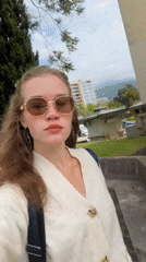 Woman in white cardigan observed outdoors on sunny day