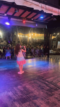 Young girl performs at outdoor nighttime show in Porlamar