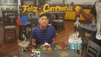 Elderly man celebrates birthday with cupcake at indoor gathering