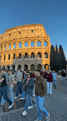 Tourists photograph Colosseum during golden hour in Rome