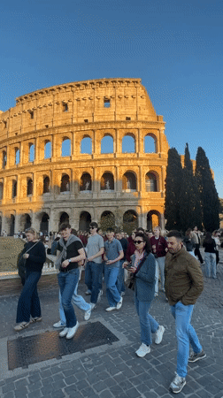 Tourists photograph Colosseum during golden hour in Rome