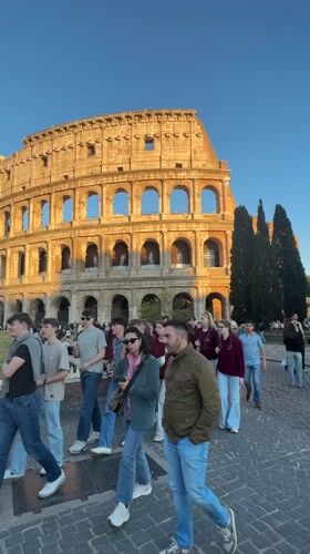 Tourists photograph Colosseum during golden hour in Rome