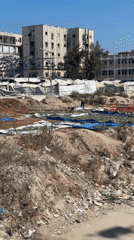 Damaged building and debris-filled open area in Gaza