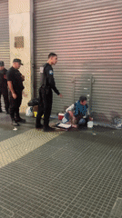 Police officers guard person on Buenos Aires sidewalk