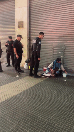 Police officers guard person on Buenos Aires sidewalk