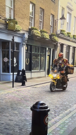 Colorfully dressed motorcyclist rides customized bike through London cobblestone streets