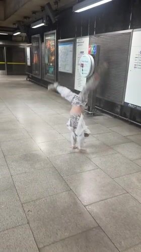 Spinning on a London Underground platform, white hoodie, patterned pants.