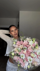 Woman poses with flower bouquet in indoor portrait session