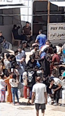 Khan Yunis residents crowd a water tanker at a displacement camp