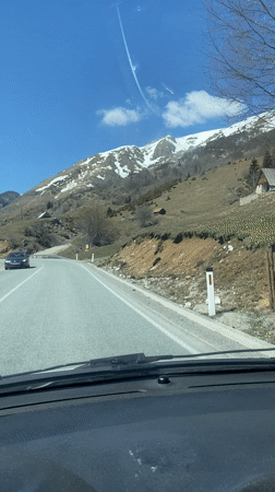 Vehicle travels mountain road in Montenegro on sunny day