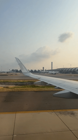 Passenger films airport view from plane window in Thailand
