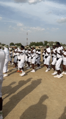 Group in white uniforms conducts outdoor training exercise