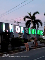 Two women visit illuminated Lhokseumawe city sign at dusk