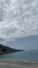 Paraglider descends over busy beach in Fethiye, Turkey