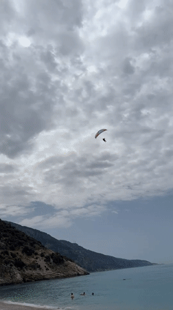 Paraglider descends over busy beach in Fethiye, Turkey