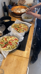 Person prepares layered vegetable tarts in Paris kitchen