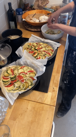 Person prepares layered vegetable tarts in Paris kitchen