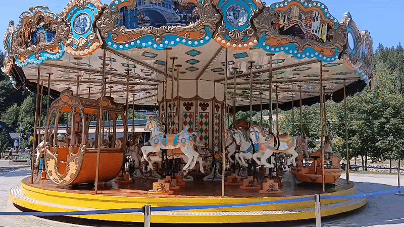Carousel rides and active construction near a mountain development