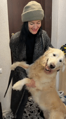 Woman and golden retriever interact in Tbilisi home hallway