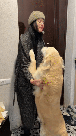 Woman and golden retriever interact in Tbilisi home hallway