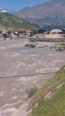 Fast-flowing muddy river documented near residential area