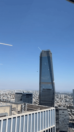 Crane lifts load atop rising Tel Aviv skyscraper
