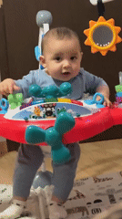 Baby plays with toys in colorful activity jumper