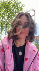 Woman in strawberry hoodie photographed outdoors during windy conditions