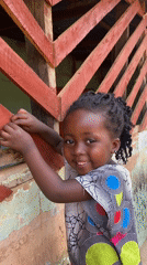 Young girl photographed smiling outside building in Kuru Dungus