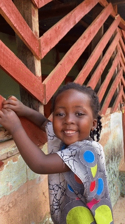Young girl photographed smiling outside building in Kuru Dungus