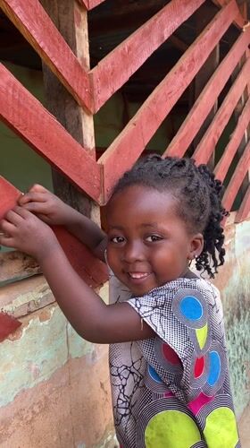 Young girl photographed smiling outside building in Kuru Dungus
