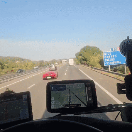 Red sports car cruising a sunny French highway with traffic