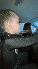 Girl in sparkly outfit talks, smiles in car backseat