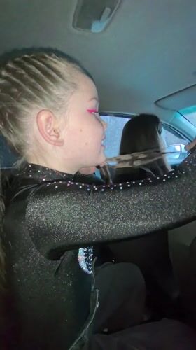 Girl in sparkly outfit talks, smiles in car backseat