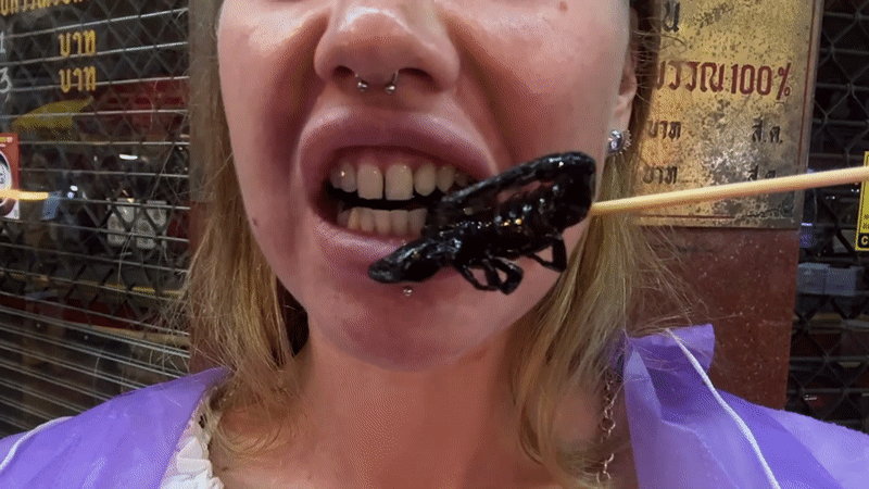 About to bite into a scorpion on a skewer in Bangkok