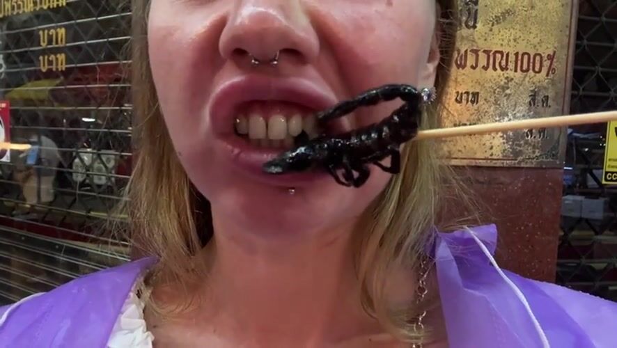 About to bite into a scorpion on a skewer in Bangkok