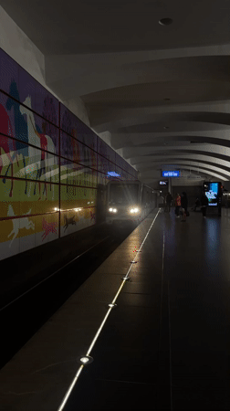 Train arrives at dimly lit subway platform with mural