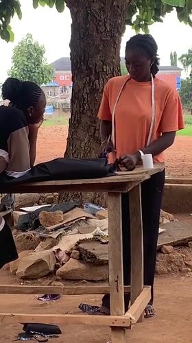 Women work with fabric at outdoor workspace in Nigeria