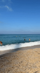 Sunny beach day with swimmers along a rocky coastline