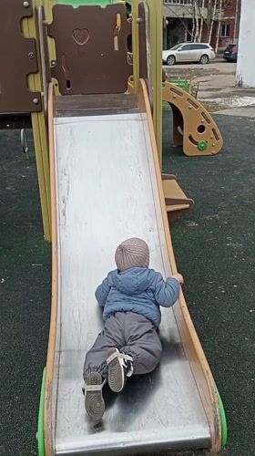 Toddler plays at Serpukhov playground while adults gather nearby