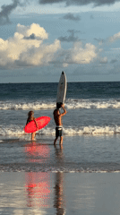 Surfers gather at Kabalana Beach during golden hour