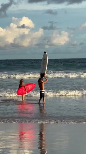 Surfers gather at Kabalana Beach during golden hour