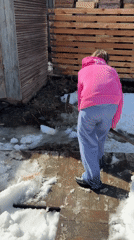 Person shovels snow on wooden deck in Zheleznodorozhny, Russia