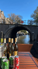Tourists enjoy drinks during afternoon Amsterdam canal boat tour