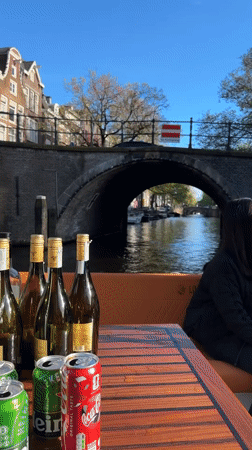 Tourists enjoy drinks during afternoon Amsterdam canal boat tour