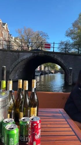 Tourists enjoy drinks during afternoon Amsterdam canal boat tour