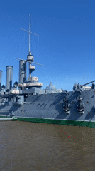 Couple tours historic Cruiser Aurora, Neva embankment in Saint Petersburg