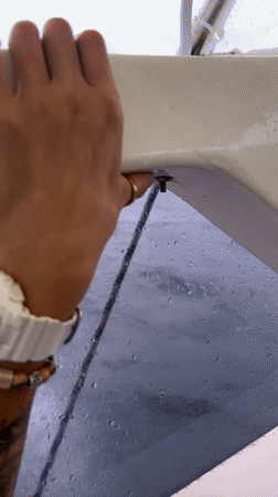 Boat operator navigates waters near Ko, Thailand during rainy conditions