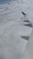 Passenger films wing view above clouds over Netherlands